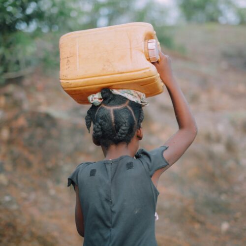 Photo of a child in Haiti carrying a liter to fetch water